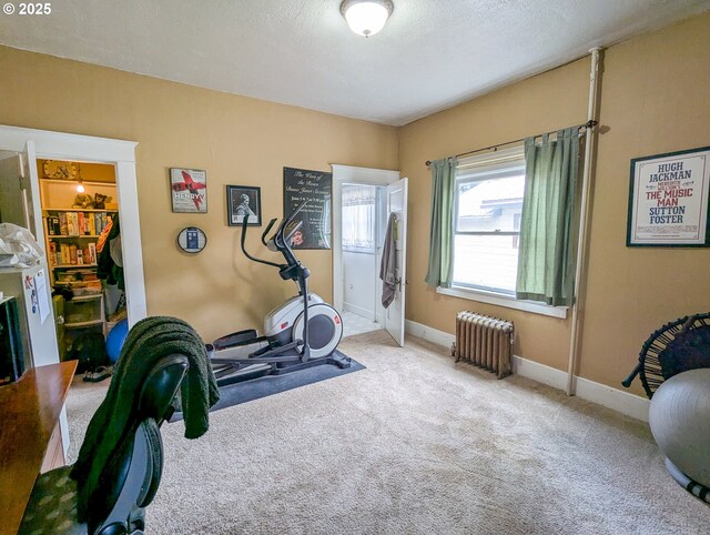 workout area featuring radiator heating unit, carpet flooring, and baseboards
