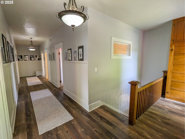 hall featuring dark wood finished floors and a wainscoted wall