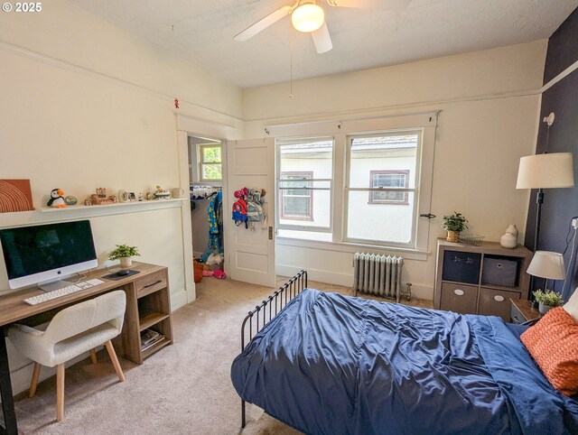 carpeted bedroom featuring radiator heating unit, an office area, and ceiling fan