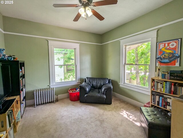 sitting room with radiator, baseboards, carpet flooring, and ceiling fan