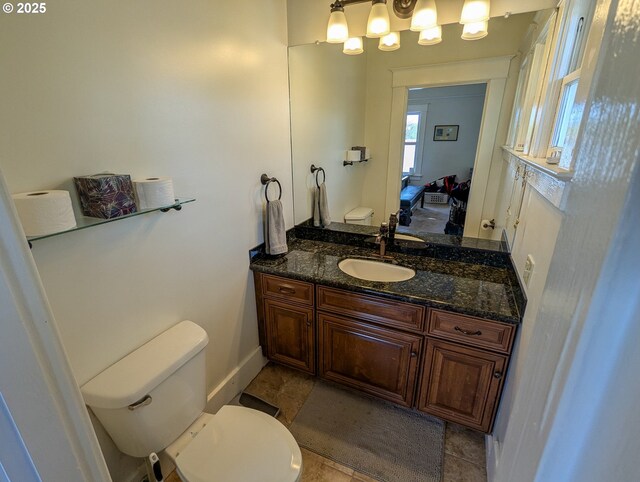 bathroom featuring toilet, vanity, and baseboards