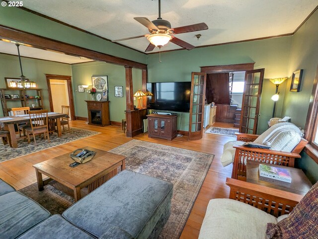 living area with a ceiling fan, wood finished floors, baseboards, and crown molding
