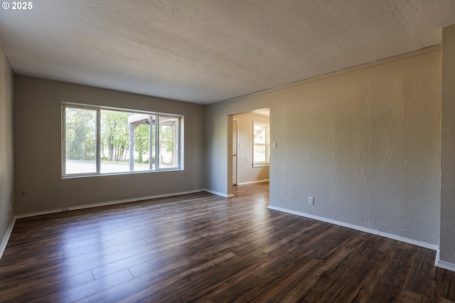 empty room featuring dark wood-style floors, baseboards, a textured ceiling, and a textured wall