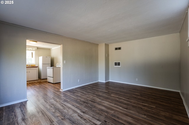 spare room featuring dark wood-style floors, baseboards, visible vents, and a sink