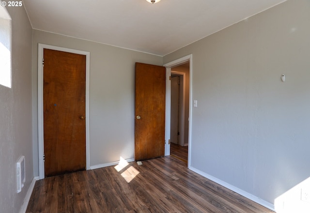 unfurnished bedroom featuring baseboards, visible vents, and dark wood-type flooring