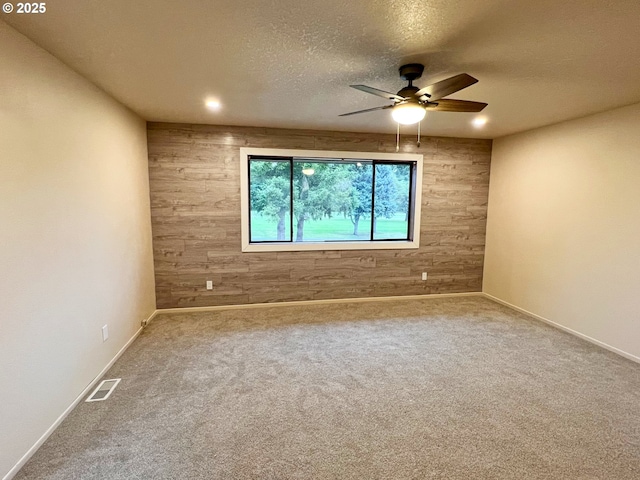 unfurnished room featuring wood walls, ceiling fan, carpet floors, a textured ceiling, and recessed lighting