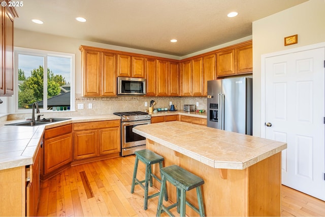 1761 S 18th Cir, Ridgefield, WA 98642 - kitchen featuring appliances with stainless steel finishes, tile countertops, light wood-style flooring, tasteful backsplash, and a center island