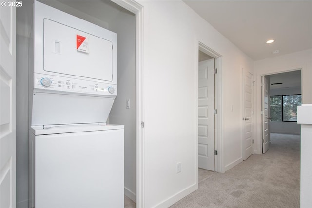 laundry area with stacked washing maching and dryer and light carpet