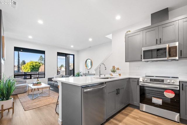 kitchen featuring appliances with stainless steel finishes, sink, gray cabinetry, and kitchen peninsula