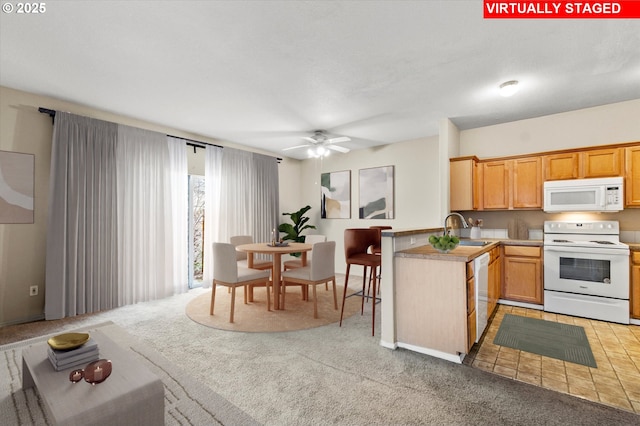 kitchen featuring sink, light colored carpet, ceiling fan, kitchen peninsula, and white appliances