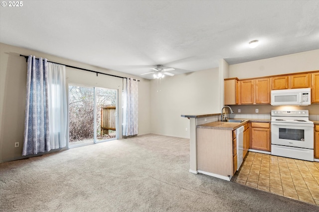 kitchen featuring light colored carpet, white appliances, kitchen peninsula, and sink