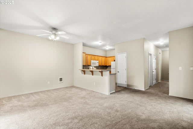 unfurnished living room featuring light carpet and ceiling fan