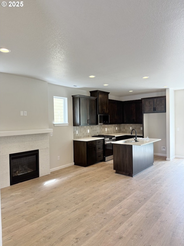 195 SE Acacia Dr, Gresham, OR 97080 - kitchen featuring stainless steel appliances, open floor plan, tasteful backsplash, dark brown cabinets, and light wood-type flooring