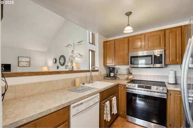 2251 SW Trachsel Dr, Beaverton, OR 97003 - kitchen featuring stainless steel appliances, a sink, brown cabinetry, light countertops, and vaulted ceiling