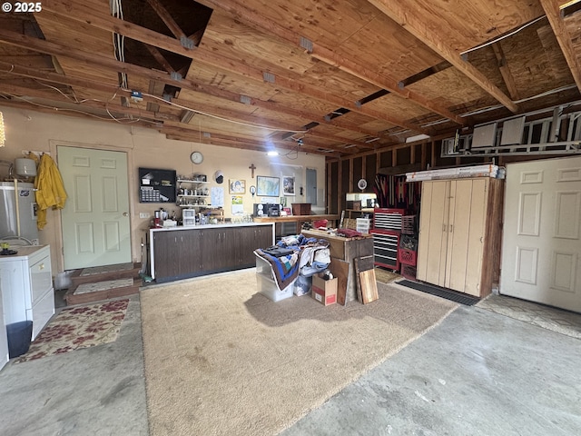 garage featuring water heater, a workshop area, and washing machine and clothes dryer