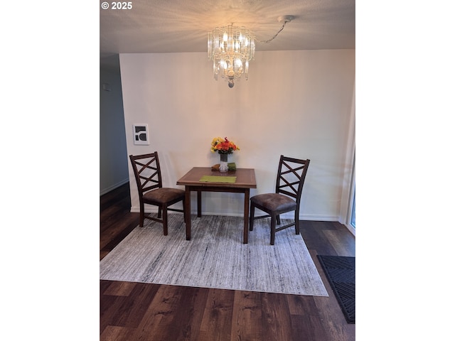 dining area featuring baseboards, a chandelier, and dark wood-style floors