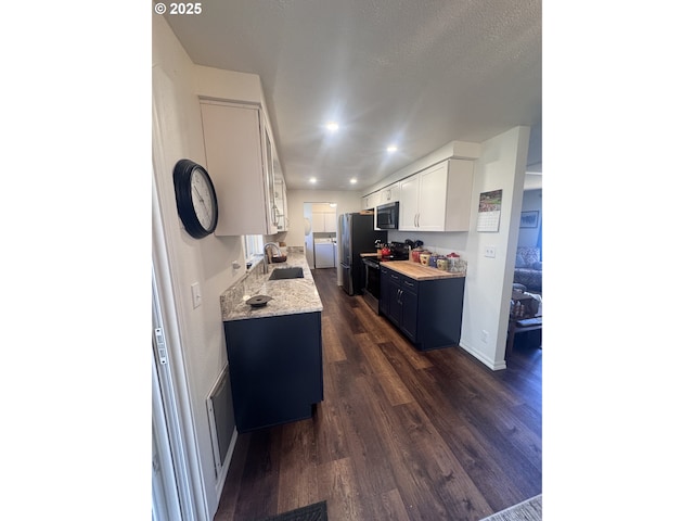 kitchen with dark wood finished floors, a sink, stainless steel appliances, recessed lighting, and white cabinetry