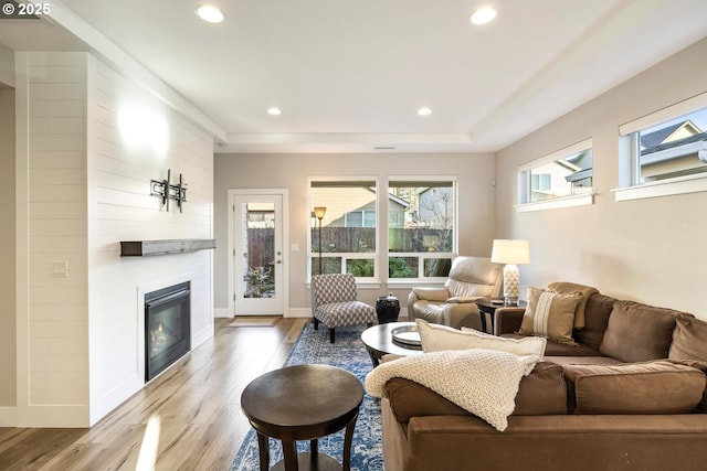 living area featuring recessed lighting, a fireplace, baseboards, and wood finished floors