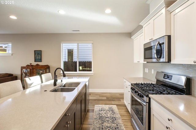 kitchen featuring tasteful backsplash, appliances with stainless steel finishes, light countertops, a sink, and recessed lighting