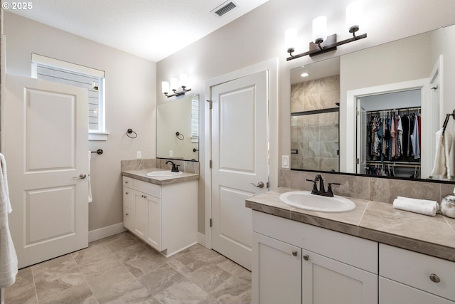 bathroom featuring visible vents, baseboards, a spacious closet, vanity, and a shower stall