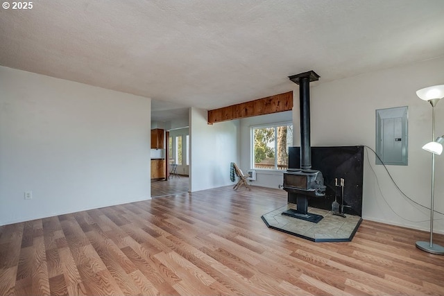 living room featuring light hardwood / wood-style floors, a textured ceiling, electric panel, and a wood stove