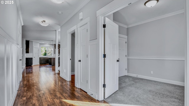 hall with dark colored carpet and ornamental molding