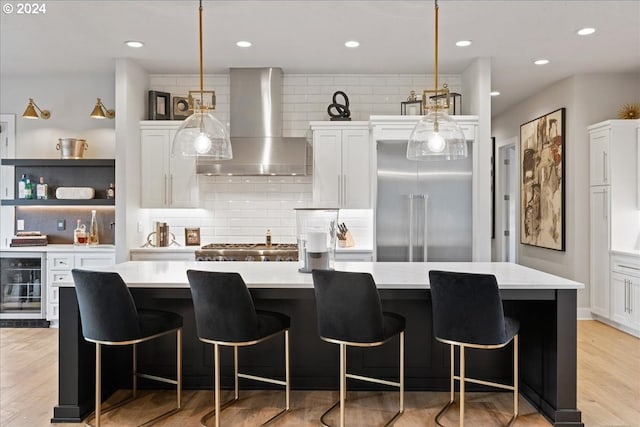 kitchen featuring wall chimney range hood, beverage cooler, appliances with stainless steel finishes, and decorative backsplash