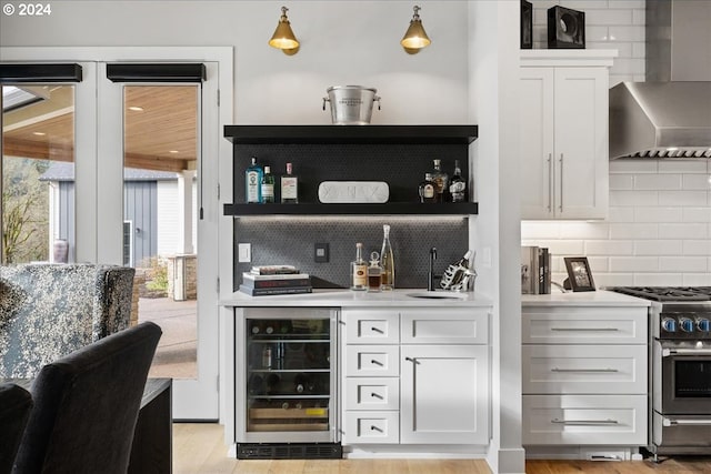 bar with high end stove, tasteful backsplash, indoor wet bar, wine cooler, and wall chimney exhaust hood