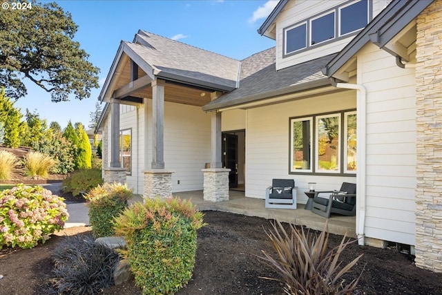 doorway to property featuring a shingled roof and stone siding