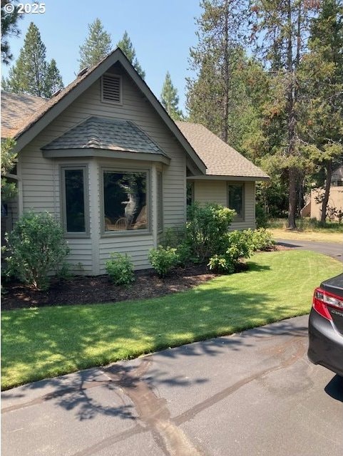 view of front of home featuring a front lawn and a shingled roof