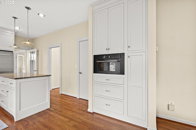 5153 Greensborough Ct, Lake Oswego, OR 97035 - kitchen with black oven, wood finished floors, dark stone countertops, white cabinetry, and decorative light fixtures