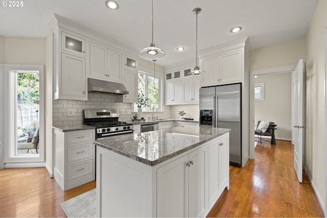 kitchen featuring tasteful backsplash, white cabinets, under cabinet range hood, and stainless steel appliances