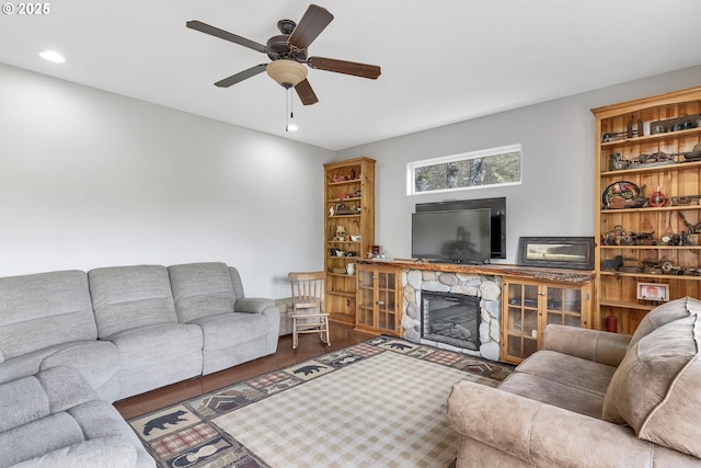 living room featuring ceiling fan, a fireplace, and wood-type flooring