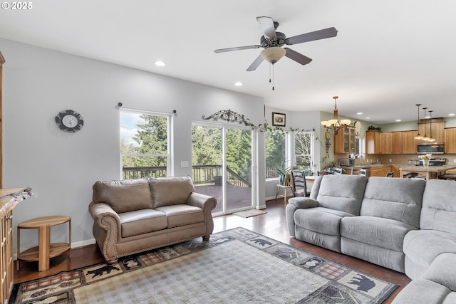 living room featuring a healthy amount of sunlight, ceiling fan with notable chandelier, and light hardwood / wood-style flooring