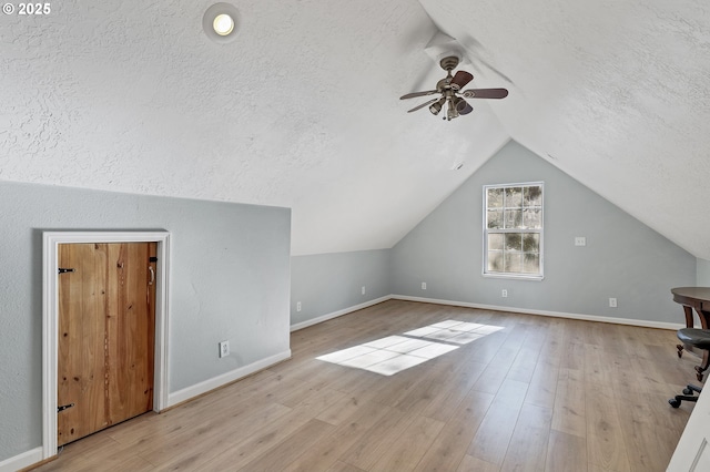 additional living space with ceiling fan, lofted ceiling, a textured ceiling, and light hardwood / wood-style flooring