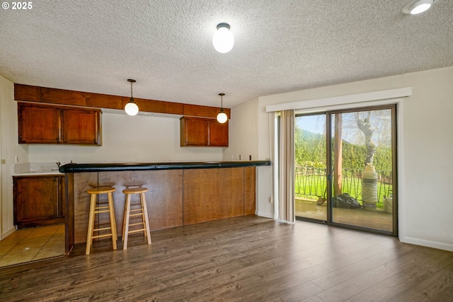 3457 Champlain Ct, Salem, OR 97304 - kitchen with brown cabinetry, a textured ceiling, dark wood-type flooring, baseboards, and decorative light fixtures