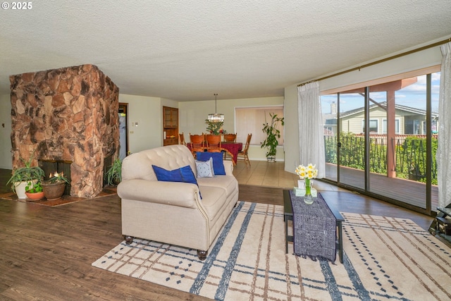 3457 Champlain Ct, Salem, OR 97304 - living room with a stone fireplace, a notable chandelier, a textured ceiling, and wood finished floors
