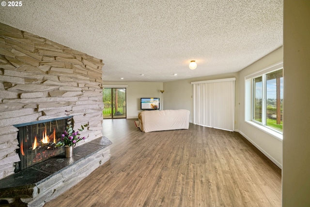 3457 Champlain Ct, Salem, OR 97304 - unfurnished living room with a textured ceiling, baseboards, a stone fireplace, and wood finished floors