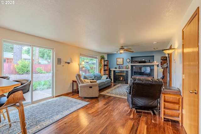 428 SE 11th Cir, Troutdale, OR 97060 - living room featuring wood finished floors, a glass covered fireplace, a ceiling fan, and a textured ceiling
