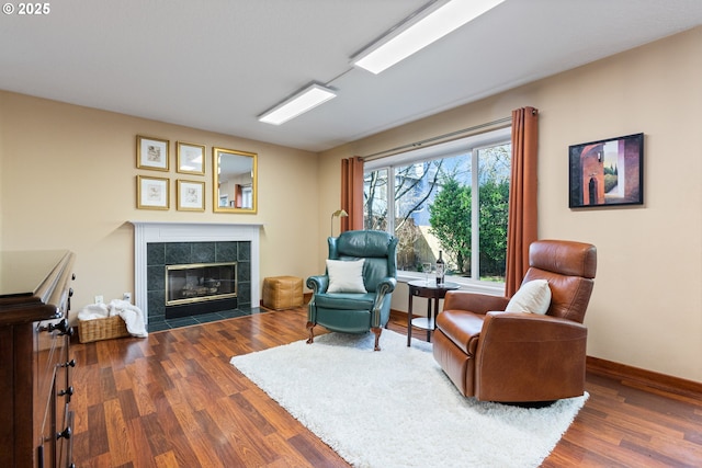 sitting room with dark wood finished floors, a tile fireplace, and baseboards