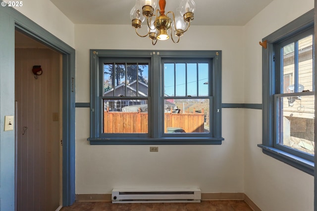 empty room with a baseboard heating unit, a wealth of natural light, and a chandelier