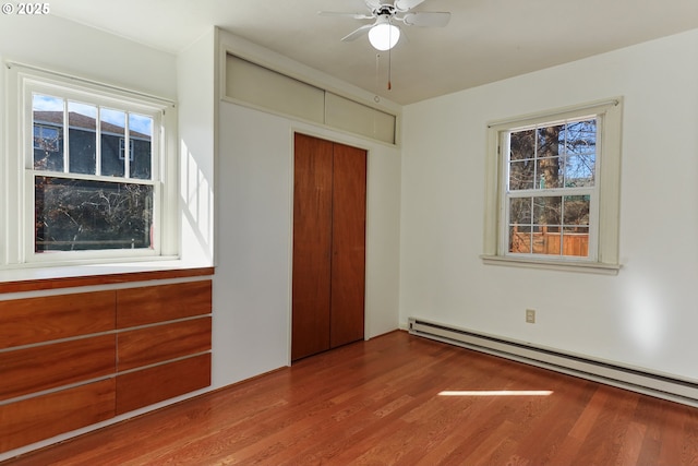 unfurnished bedroom featuring hardwood / wood-style floors, a baseboard radiator, and a closet