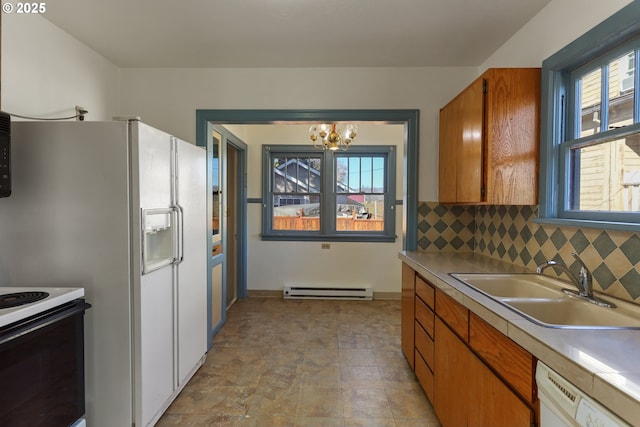 kitchen with sink, decorative backsplash, a baseboard heating unit, a notable chandelier, and white appliances