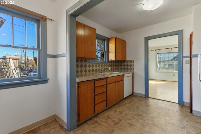 kitchen with white dishwasher, sink, and tasteful backsplash