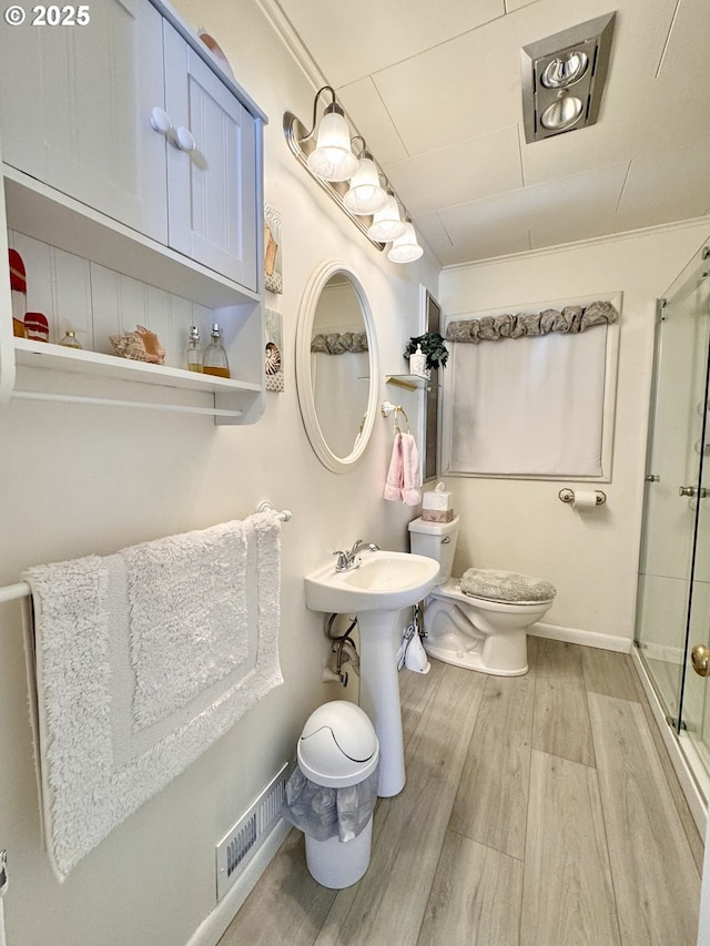 bathroom featuring hardwood / wood-style floors, sink, ornamental molding, walk in shower, and toilet