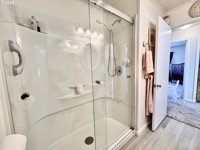 bathroom with ornamental molding, hardwood / wood-style floors, and a shower with shower door