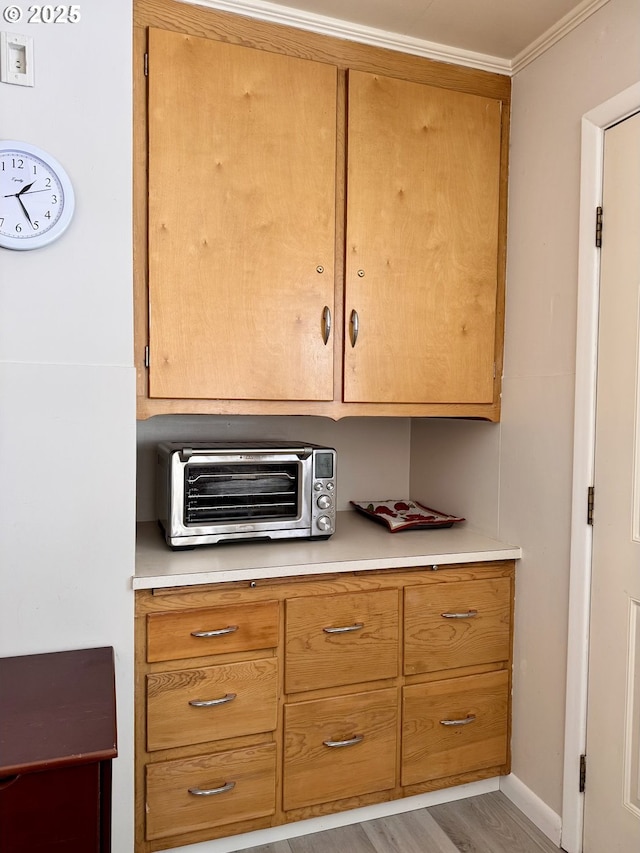 kitchen with ornamental molding and light hardwood / wood-style floors