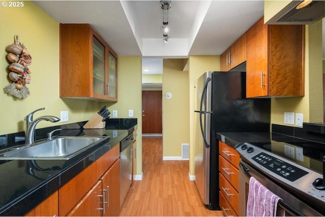 6600 SE Division St Unit 304, Portland, OR 97206 - kitchen with visible vents, brown cabinetry, a sink, light wood-style flooring, and stainless steel appliances
