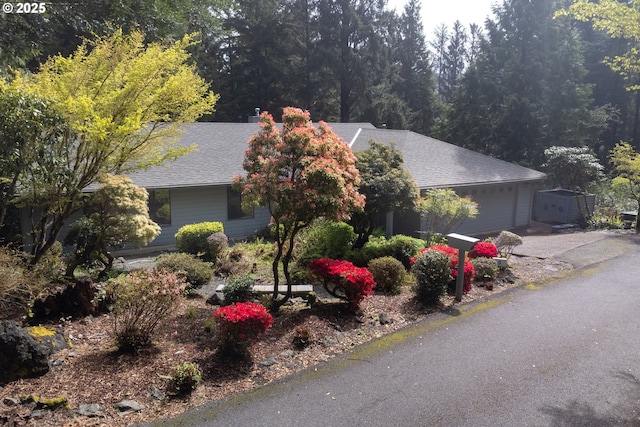 5 Woodthrush Ln, Gleneden Beach, OR 97388 - obstructed view of property with a shingled roof, a garage, a storage shed, and driveway