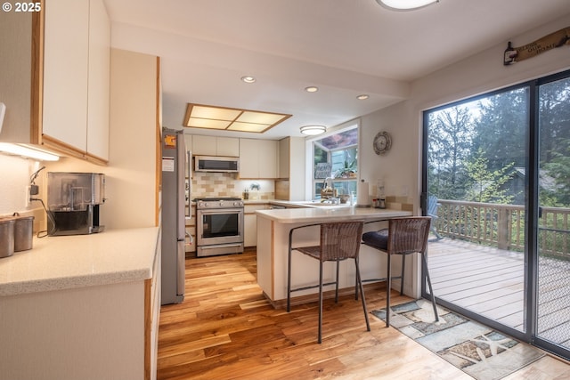 5 Woodthrush Ln, Gleneden Beach, OR 97388 - kitchen with appliances with stainless steel finishes, light wood finished floors, a peninsula, decorative backsplash, and recessed lighting